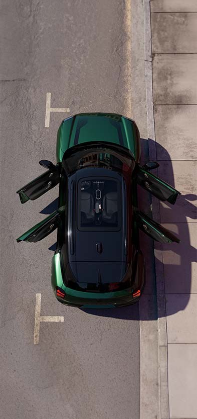 Draufsicht auf einen parkierenden vollelektrischen MINI Aceman in Orange, Türen und Panoramadach sind geöffnet